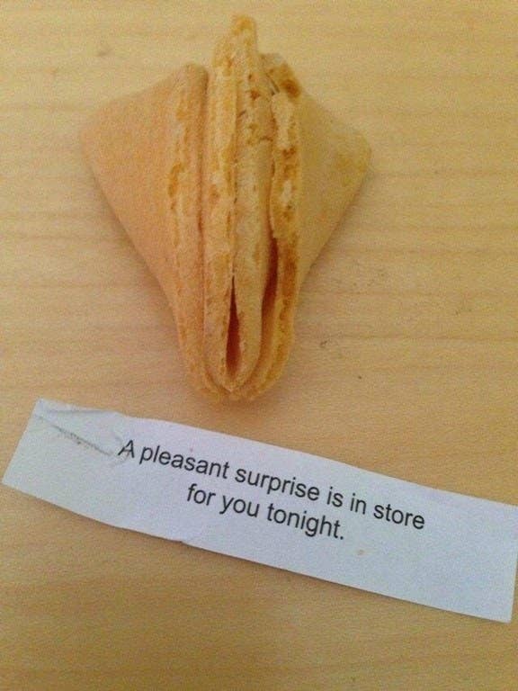 A fortune cookie broken in half and a message that says a pleasant surprise is in store for you tonight