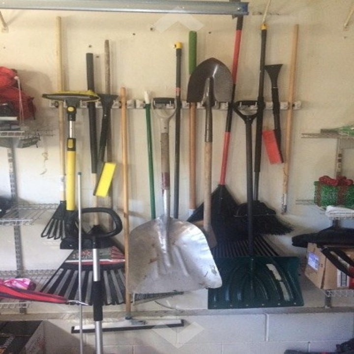 garage wall with a variety of long handled tools stored on it vertically