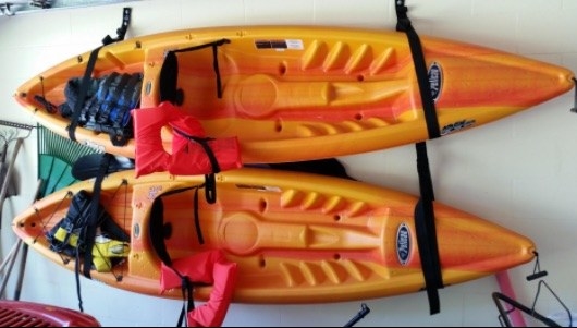 reviewer&#x27;s pic of two kayaks mounted flat against a garage wall with straps