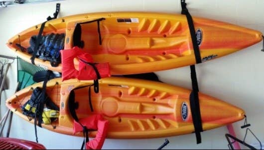 reviewer's pic of two kayaks mounted flat against a garage wall with straps