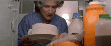 A GIF of Mrs. Doubtfire sticking her head into cake frosting to disguise herself