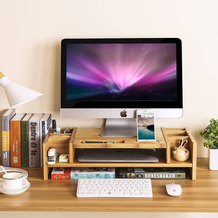 Get it from Amazon for $42.99.Promising review: "I have been looking for a monitor riser for several weeks since starting my new job. This one really caught my eye as I am a major fan of bamboo products for their durability and sustainability. I loved that this one had several cubbies and even a cup holder. The cell phone cubby is very useful for keeping my smartphone nearby, and even when I have it plugged in, it works well. The other cubbies are handy for holding pens, pencils and highlighters and the cup cubby holds both my coffee cup and cup like a charm. The smaller cubby is nice to hold paperclips and bobby pins (you never know when you need one!) and other small odds and ends. The larger cubby in the back accommodates a variety of things and I have a little lamp that fits perfectly in one of them. The finish is a very natural look with just enough stain to bring out the wood grain and not too much varnish. The riser itself is about three inches which is exactly what I needed for my workspace to bring my monitor up to eye level and feel more comfortable than resting on my desk. There is a small cutout in the back to accommodate wires where I could have it flush against the wall if I needed, which I think is nice. Overall I am extremely pleased with my purchase and consider it money well spent." —Lacie