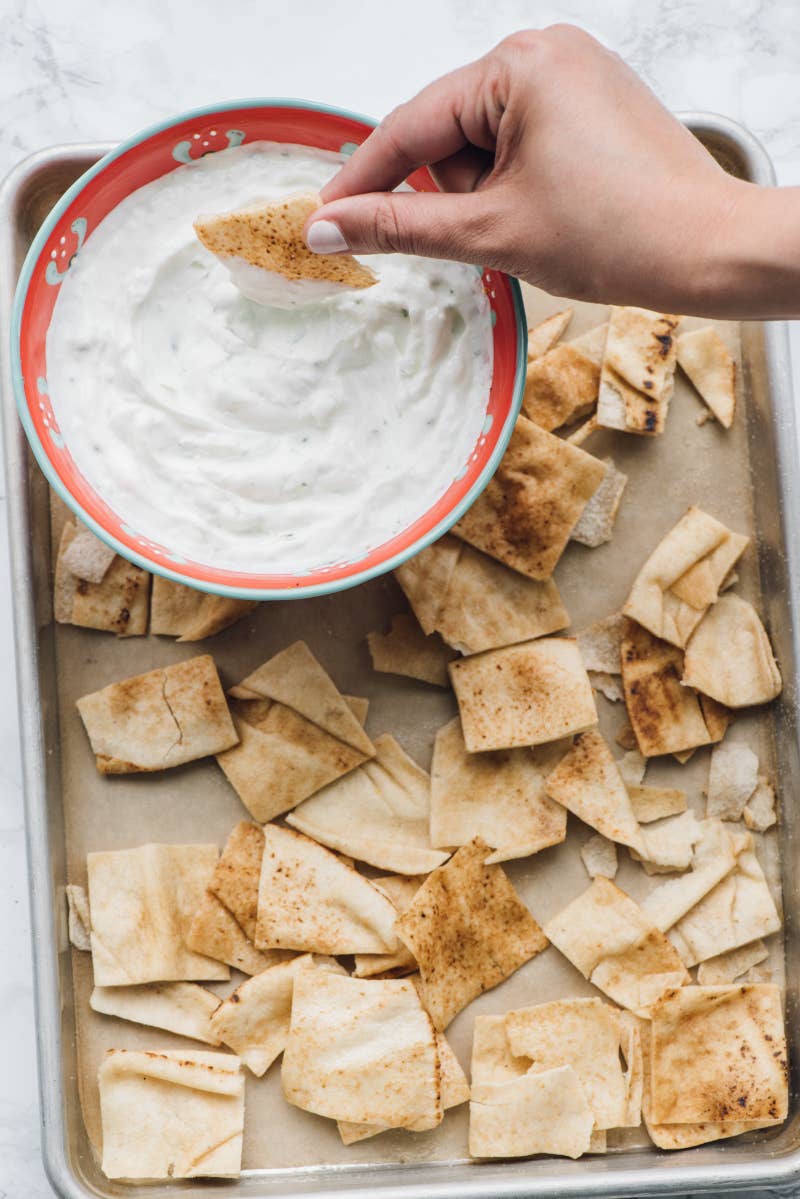 Ingredients:Chips: 1 piece of pita bread, cut into 8 wedges; 2 tablespoons extra virgin olive oil; kosher salt, to taste.Tzatziki: ¾ cup Greek yogurt; 1 cucumber; 1 tablespoon lemon juice; 1 tablespoon olive oil; ¼ teaspoon lemon zest; ¼ teaspoon minced garlic; ¼ teaspoon kosher salt; ¼ teaspoon ground black pepper.To make:Chips: Preheat oven to 400°F. Toss cut pita with olive oil and kosher salt and spread onto a baking sheet. Cook for 7 minutes until crisp and golden. Let cool. Serve with Greek yogurt tzatziki.Tzatziki: Grate the cucumber and squeeze in a paper towel to remove excess moisture. Mix with yogurt, lemon juice, olive oil, lemon zest, garlic, salt, and pepper.