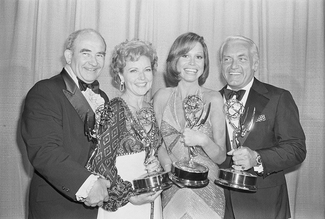 Black-and-white photo of the four smiling stars holding awards