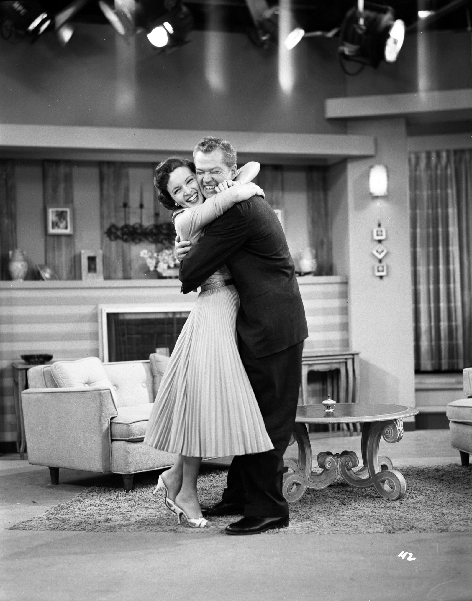 Betty and Bill smiling and embracing in a living room