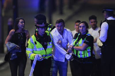 Police escort a member of the public as they clear the scene of a terror attack on London Bridge in central London on 3 June 2017.