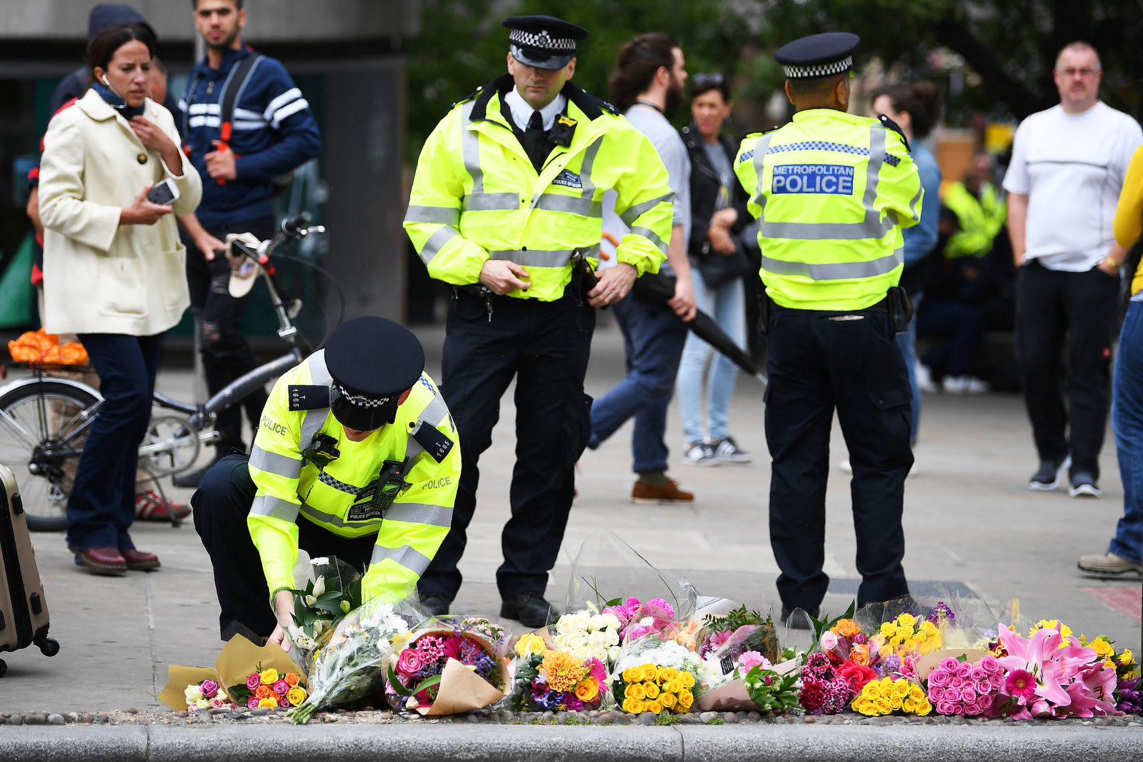A police officer lays flowers at a pedestrian crossing by Borough Market, left in tribute to the victims of the 3 June attacks.