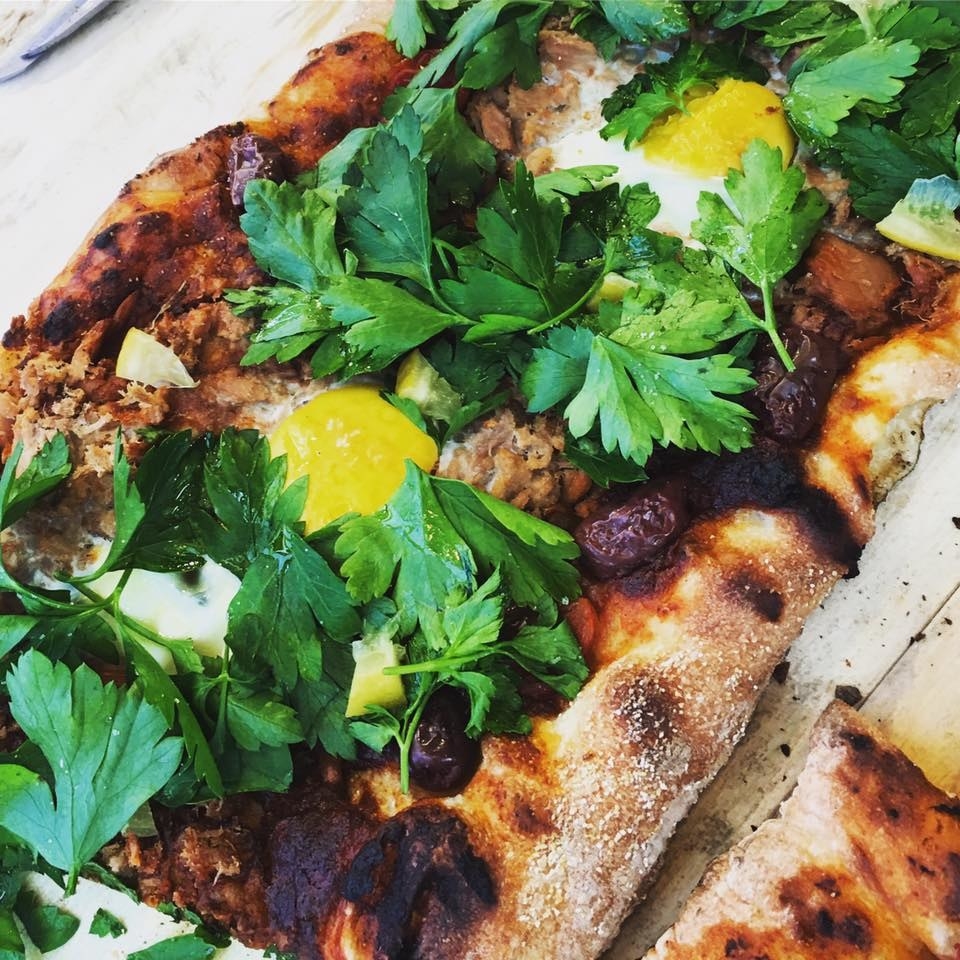 Baked in a stone deck oven right in the middle of Times Square, Rock Pizza Scissors makes fresh handmade pizzas using unique, seasonal toppings and dough made by hand throughout the day. The Tunisian Tuna is topped with harissa, tuna, olive, potato, fried egg, fresh parsley, and preserved lemon.