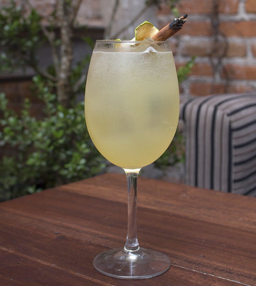 Ingredientes: - Uvas- Jugo de manzana- Licor de hierbas- Gin- Agua tónica- Manzana deshidratada- Varita de canelaServir en copa de vino tinto.