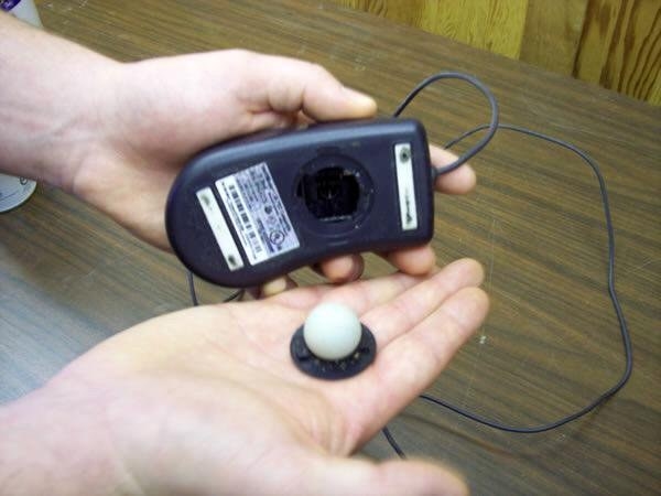 A photo of a hand holding an old fashioned computer mouse with the bowl inside of it on the person&#x27;s other hand