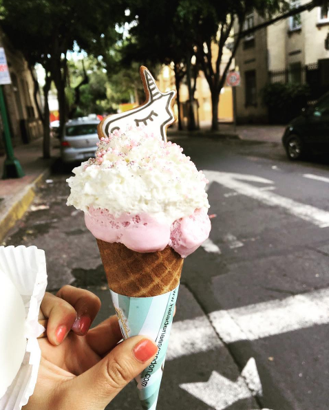 Lleva crema batida, una galletita en forma de cabeza de unicornio y chispitas brillantes.