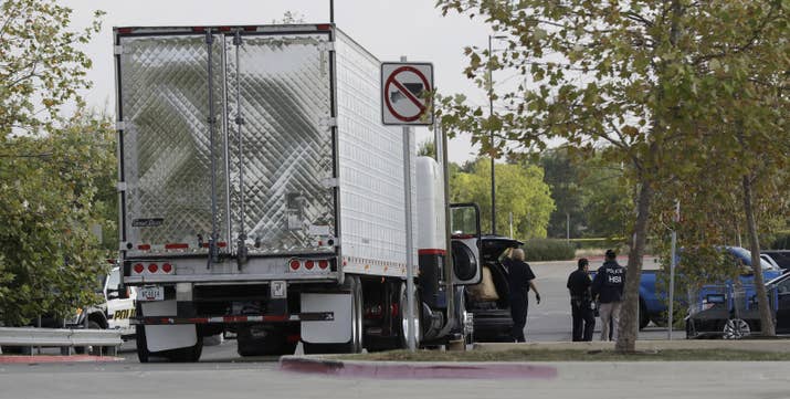 San Antonio police officers investigate the scene where eight people were found dead in a tractor-trailer.