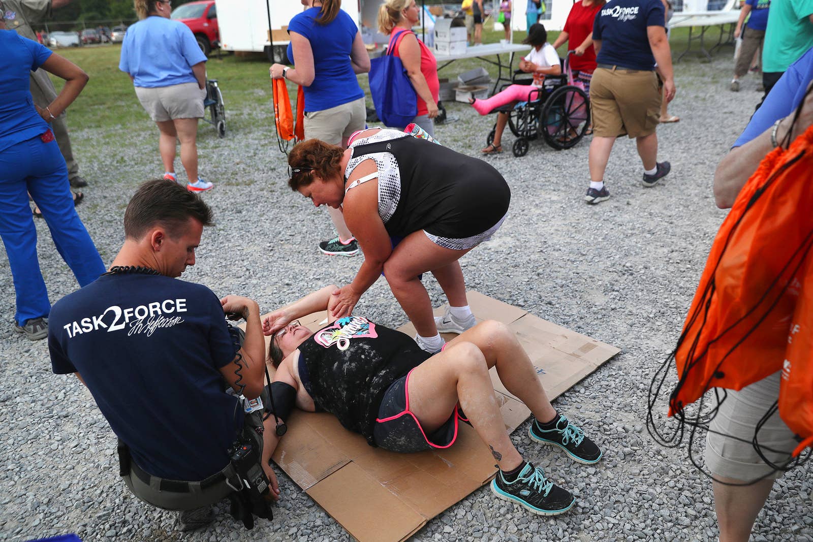Medical volunteers assist a woman who collapsed while awaiting medical services in Wise on July 21.