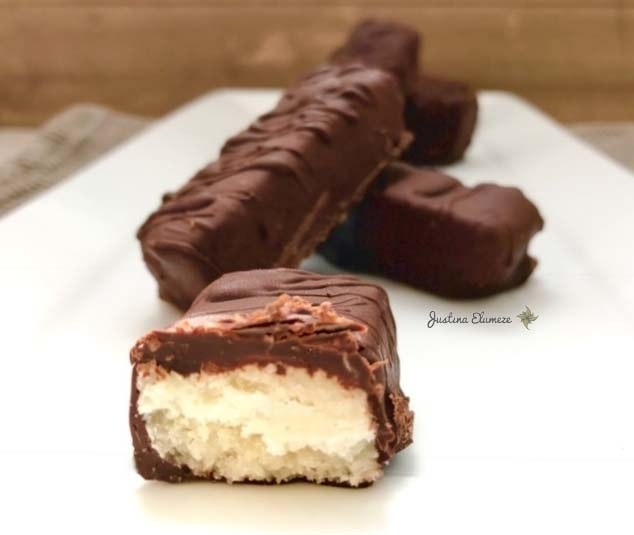 I love most things coconut, from coconut milk to coconut water, so it stands to reason that I’d enjoy a Bounty bar… or two.I used to eat them quite regularly along with Cabana bars (whatever happened to them? They were THE best chocolate bars ever!) when I were a wee lass.However, long before I even knew anything about the Paleo diet or clean eating, I kind of suspected that shop bought Bounty bars weren’t the healthiest of treats, regardless of the fact that they were supposedly full of healthy coconut.Fast forward a few years and with a newly found knowledge of healthy eating, my suspicions were confirmed as soon as I was able to decipher that the ingredients listed on a Bounty wrapper were totally indecipherable… unless you were a scientist.The amount of unpronounceable additives, preservatives and colourings involved in that small bar of chocolate were shocking!It was around this time that I made a conscious decision to solely consume foods which contained ingredients that I didn’t need a degree in biochemistry in to pronounce.With a liking for the occasional childhood treat but a total dislike for the unhealthy ingredients within them, it made perfect sense to create healthy versions which contained no additives or similar gunk and thus, the Paleo Bounty was born!As I’m not that much of a chocaholic, I’ve not made many batches of these over the years, but whenever I do, I can guarantee that they don’t remain in my household for long.I’m serious, these bars of natural goodness are literally gone in 60 seconds!Ingredients 2 cups desiccated coconut 3 tbsp. coconut oil 4 tbsp. honey/agave syrup Pinch of sea salt (optional) 1 tsp. vanilla bean paste 100g dark chocolate (I used Menier Swiss Chocolate)Instructions Mix all ingredients (except chocolate) in a blender for approximately five minutes so everything fully combines. Remove and mould/roll the mixture into individual bars and set aside on a grease proof tray. Melt the chocolate and individually roll the bars in the chocolate before placing back on the tray and placing in the fridge until the bars have cooled and hardened. Remove and enjoy!