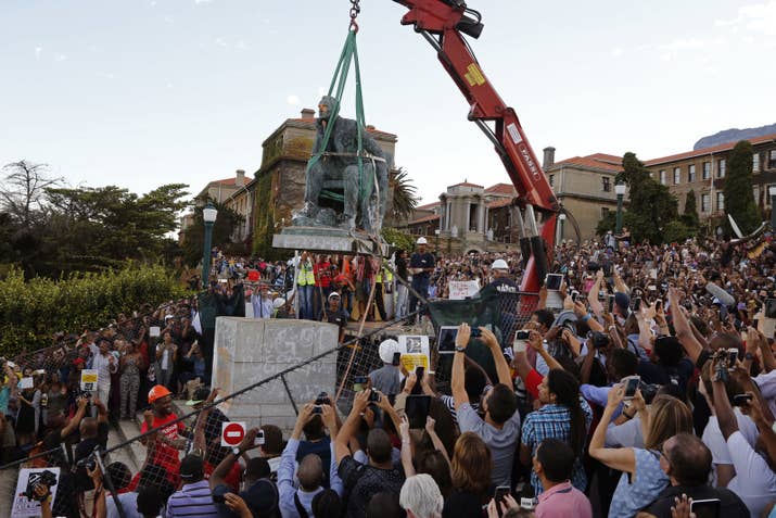 Cheering students surround the decades-old bronze statue of British colonialist Cecil Rhodes as it is removed from the campus at Cape Town University, Cape Town, South Africa, April 9, 2015.
