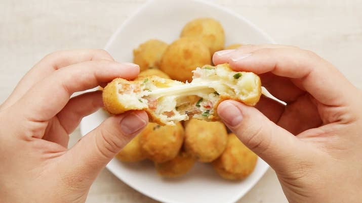 Rendimento: 20-25Você vai precisar de:4 batatas médias, descascadas e cortadas em pedaços2 colher de chá de sal1 xícara de bacon frito½ xícara de cebolinha picada½ xícara de queijo parmesão ralado1 colher de chá de pimenta1 colher de sopa de leite½ xícara de m queijo muçarela em cubos2 xícaras de farinha de trigo5 ovos batidos2 xícaras de farinha de roscaÓleo para fritarModo de preparo:1. Aqueça água em uma panela até a fervura e adicione as batatas, 1 colher de chá de sal e mexa.2. Cubra e ferva por 20-25 minutos até que um garfo possa furar as batatas com facilidade.3. Seque as batatas em uma toalha, permitindo que resfriem para remover o excesso de umidade, então transfira para um refratário grande.4. Amasse as batatas até que não haja nenhum pedaço grande.5. Adicione o bacon, a cebolinha, o parmesão, a outra colher de sall, a pimenta e o leite. 6. Misture até incorporar.7. Pegue um pouco da massa, abra na mão e recheie com um cubo de muçarela. Enrole fazendo uma bolinha.8. Separe a farinha de trigo, os ovos batidos e a farinha de rosca em potes diferentes.9. Empane as bolinhas passando primeiro na farinha de trigo, tirando o excesso, depois nos ovos batidos e por último na farinha de rosca.10. Aqueça o óleo em fogo médio.11. Frite 2-3 bolinhas de cada vez até dourarem e deixe secar em papel toalha.12. Aproveite!