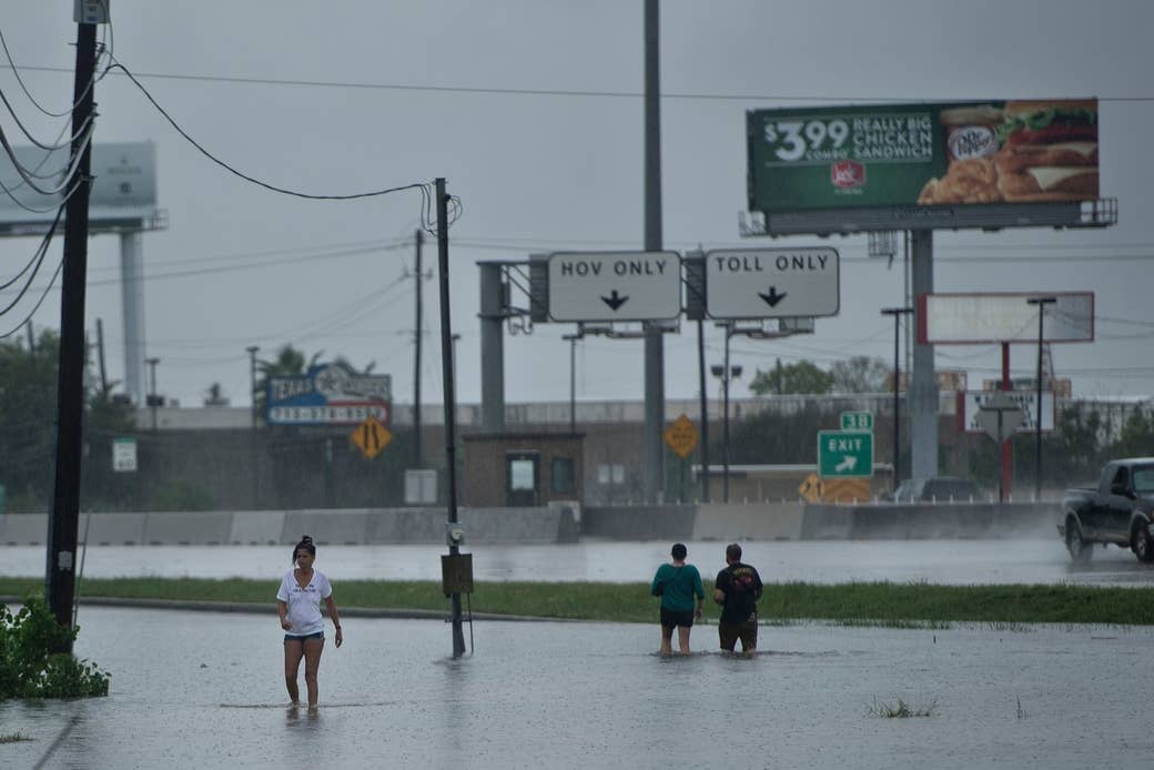 Personas caminando por calles inundadas luego del paso del huracán Harvey, 27 de agosto de 2017 en Houston.