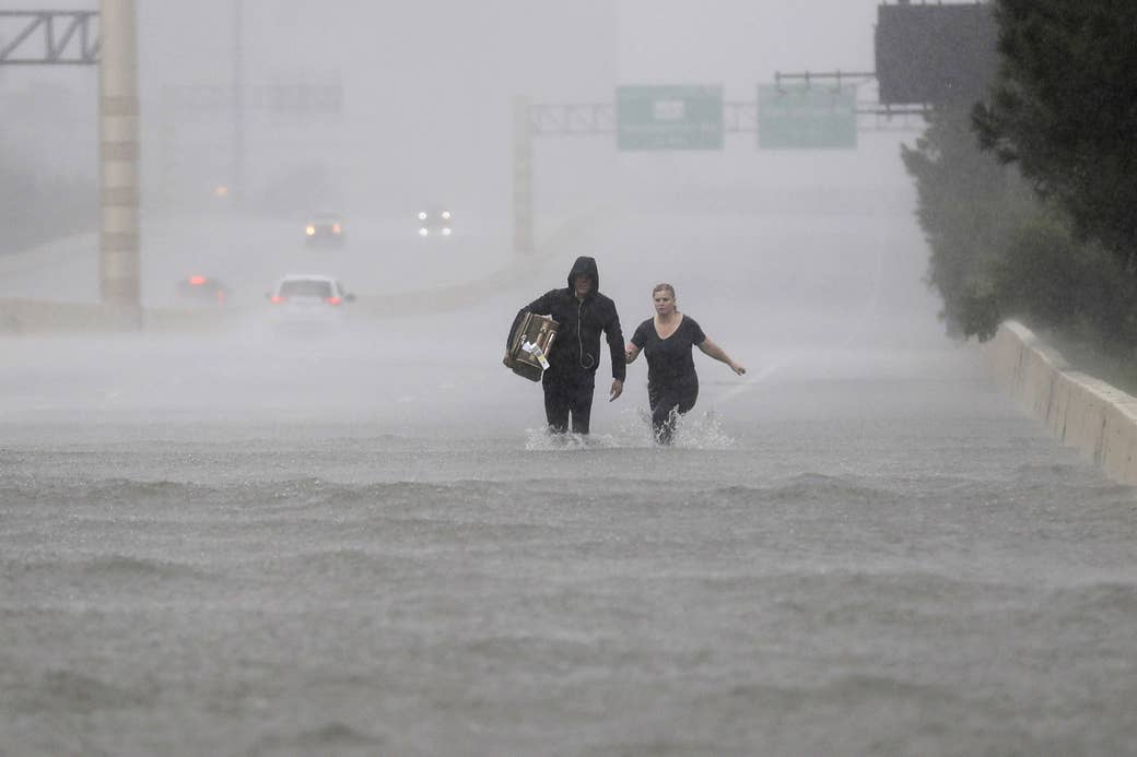 Dos personas caminan por una sección de la Interestatal 610 inundada a causa de la tormenta tropical Harvey, 27 de agosto de 2017, en Houston.
