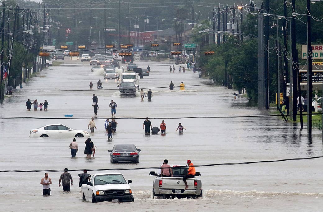 Personas caminando en medio del agua en Telephone Road en Houston, el 27 de agosto de 2017.