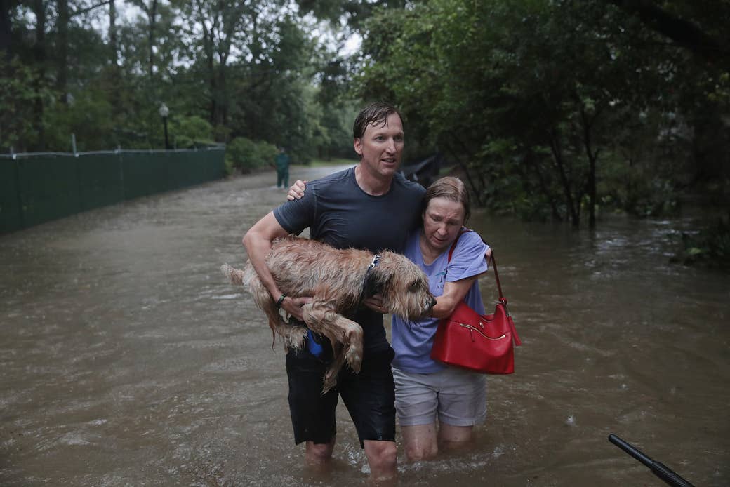 Andrew White (izquierda) ayuda a una vecina en la calle luego de rescatarla de su hogar con su bote en el lujoso vecindario de River Oaks, luego de que fuera inundado por el paso del huracán Harvey el 27 de agosto de 2017, en Houston.