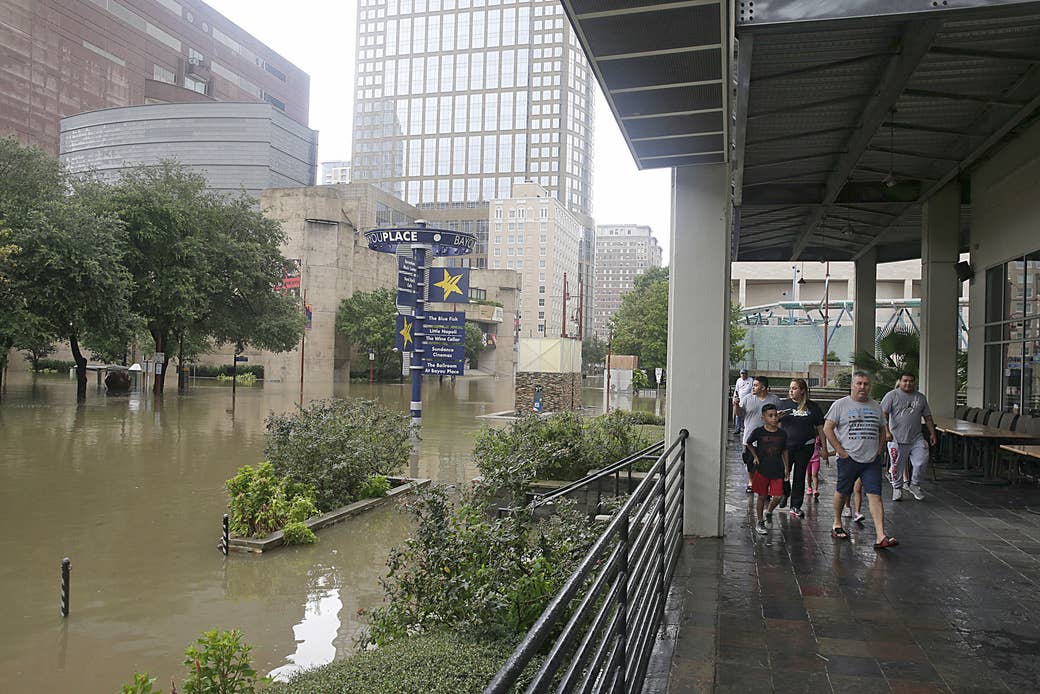Personas caminando por Bayou Place mientras observan el inundado distrito teatral de Houston, el 27 de agosto de 2017 mientras la ciudad lucha con la tormenta tropical Harvey y las inundaciones resultantes.