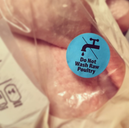 Close-up of a &quot;Do Not Wash Raw Poultry&quot; sticker on chicken packaging