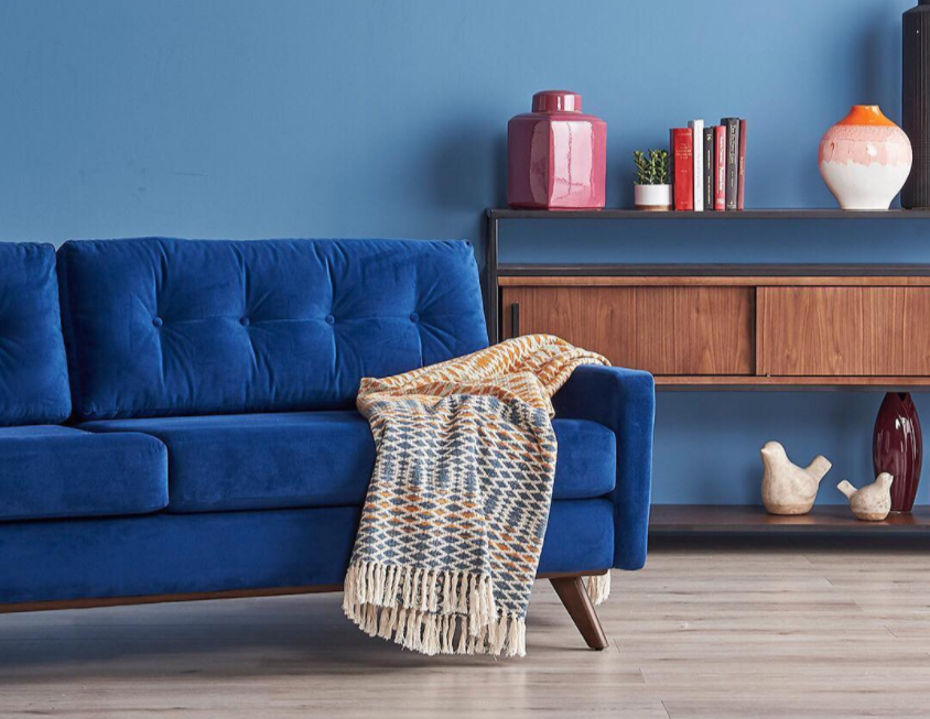 The blue sofa with a multicolored throw hanging off of it