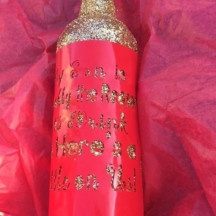 buzzfeed community member's glitter-covered bottle that says "my son is probably the reason you drink, so here's a bottle of wine on us"