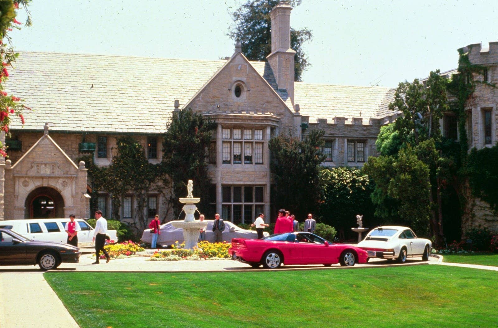 Luxury and high-end sports cars line the driveway of Hefner's Playboy Mansion during a party in 1991.