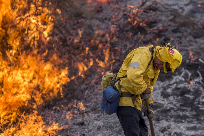 A firefighter recoils from the heat of flames.