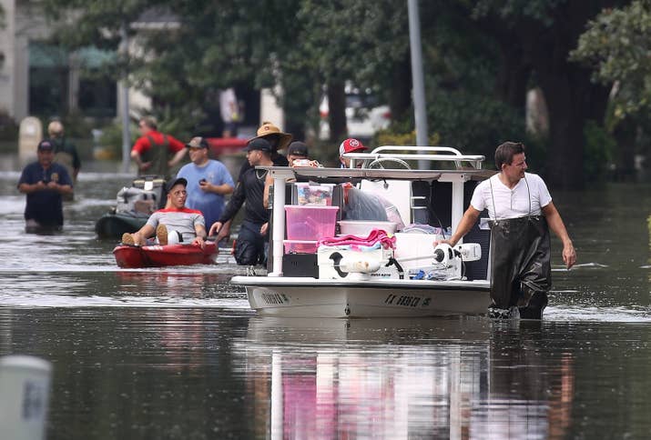 People use boats to bring items out of homes in Houston Sunday.
