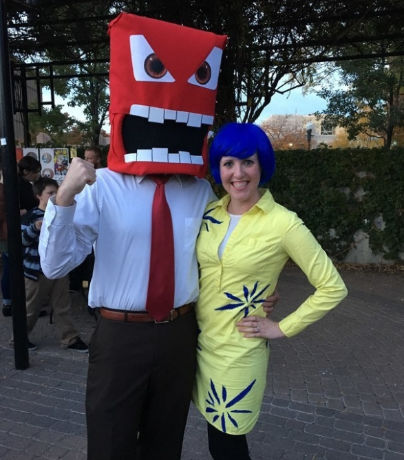 Someone wearing a blue wig and yellow dress, and another wearing a giant, angry red head