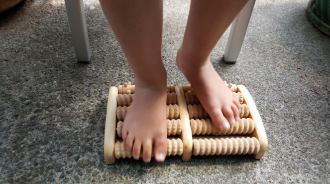 Reviewer using the abacus-like foot roller on their feet 