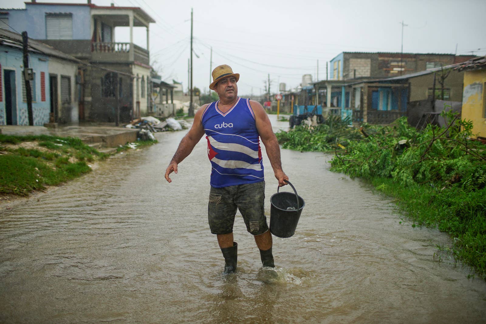 A man with a bucket stands in floodwaters.