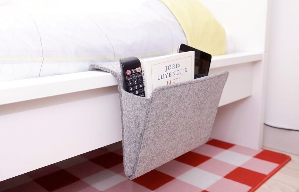 the bedside caddy with a remote and other items inside
