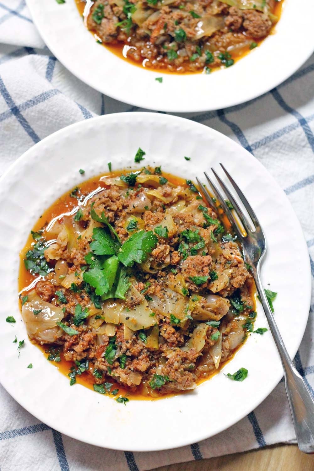 Two bowls of stuffed cabbage soup with fresh herbs.