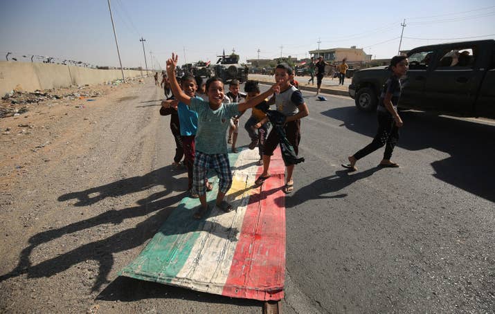 Iraqi children step on a Kurdish flag as forces loyal to the central government in Baghdad advance toward the center of Kirkuk on Monday.