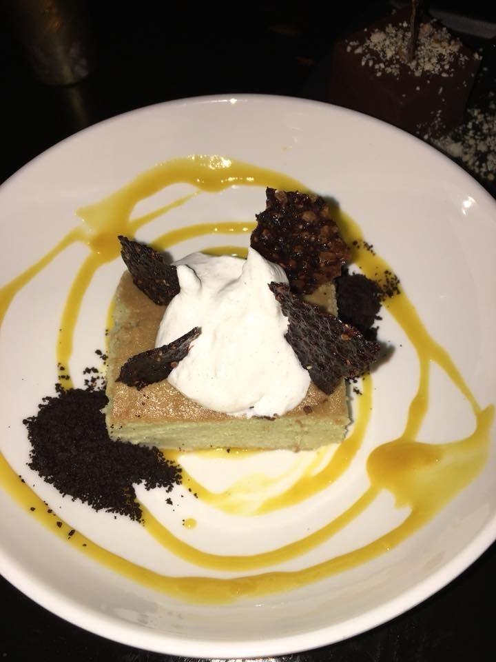 A block of matcha pound cake soaked in condensed milk is complemented by crunchy chocolate crumb and mango coulis, and topped with chocolate sesame tuile.