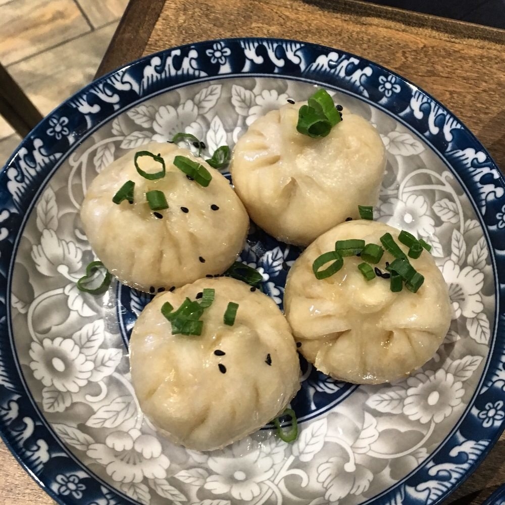 About the size of a baby's fist, the Pan-Fried Pork Buns feature crispy bottom and soft, fluffy interior with savory pork meat inside the buns. The pork buns are topped with scallions and black sesame.
