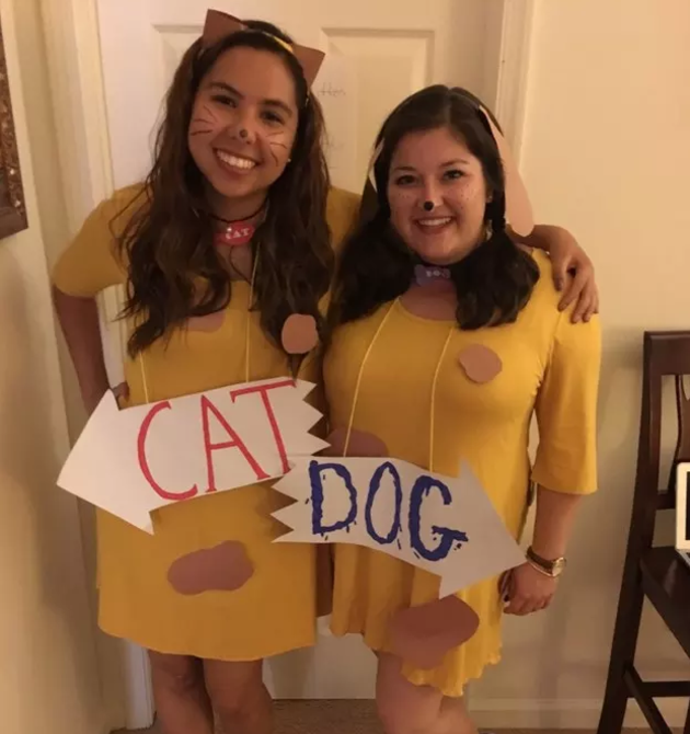 Two women hugging and wearing &quot;Cat&quot; and &quot;Dog&quot; signs