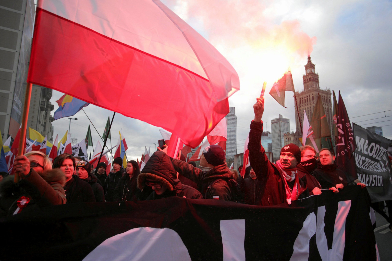 Protesters light flares and carry Polish flags during Saturday's rally.