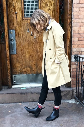 BuzzFeed editor, Rebecca O'Connell wearing the black rain boots with a trench coat outside