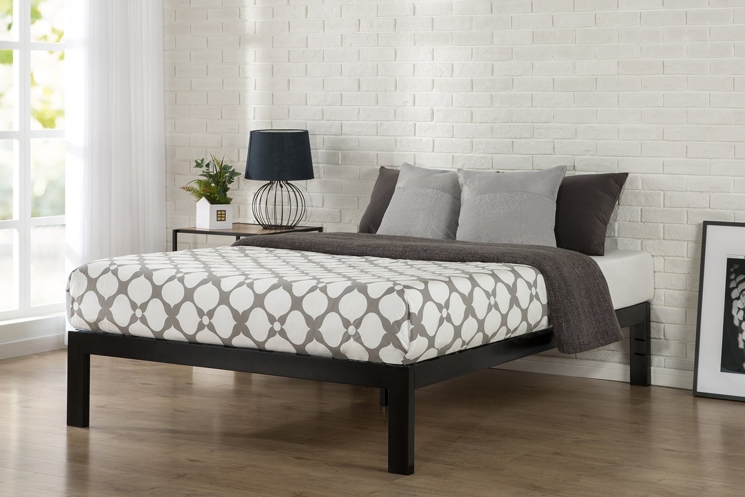 bed frame with bedding and nightstand with lamp