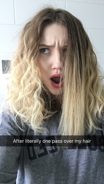 BuzzFeed editor with thick, curly hair who's straightened one section of her hair with the brush and has an expression of shock on her face