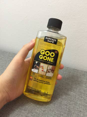 buzzfeed writer holds bottle of yellow liquid that says goo gone 