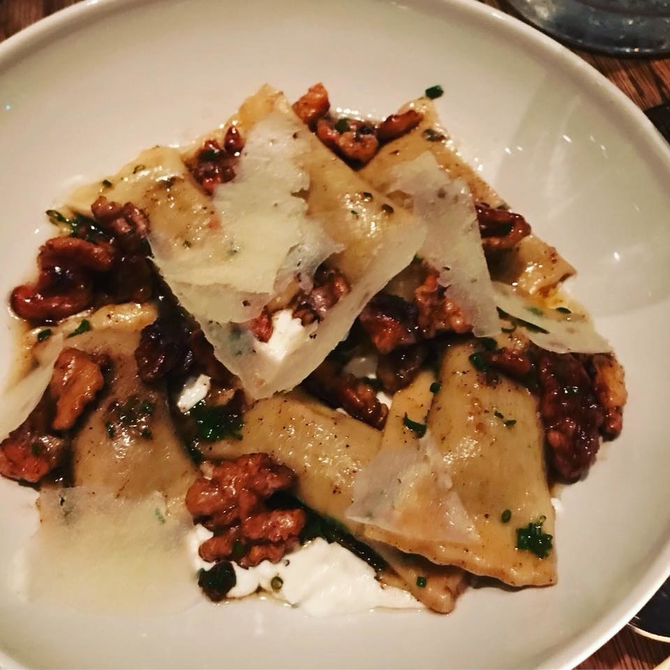 This signature fall dish features ravioli-style pasta filled with tomato-spiced kabocha squash puree over creamy ricotta and crunchy candied walnuts in a brown butter sauce.