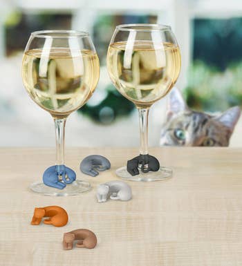 Two wine glasses with different colored kitty drink markers around the stem