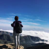 reviewer standing at the top of a mountain wearing the backpack