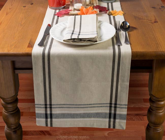 wood dining table with burlap stripe runner on it