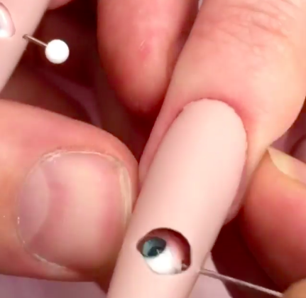 Nail technicians first had to build a lil' fake eyeball. Then they had to drill a hole into the (presumably) fake acrylic nail to insert the eyeball into the nail.